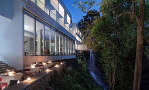 A modern building with large windows overlooking a waterfall.