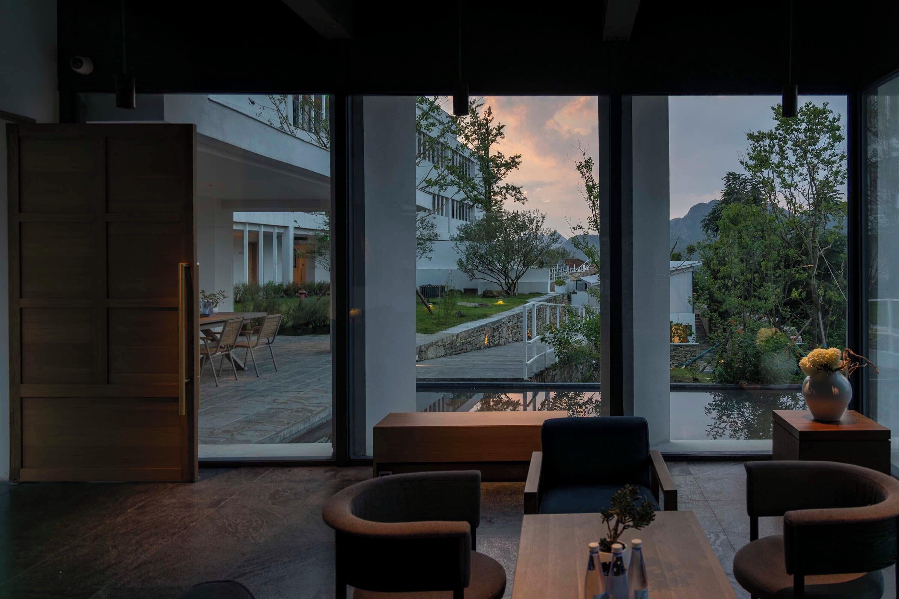 Un interior moderno con ventanas amplias, una mesa de madera y dos sillas.