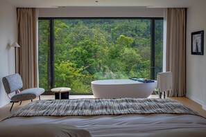 A modern bedroom with a large window, a bathtub, and a bed. - Zhiye Resort Hotel (Anshun)