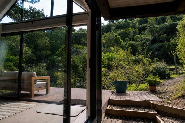 A modern outdoor patio with a wooden bench and a potted plant.