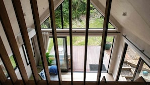 A high-ceilinged room with a large sliding glass door leading to an outdoor deck.