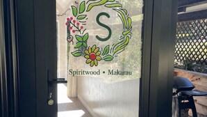 A door with a frosted glass panel featuring a monogram and the words 'Spiritwood Makarau.'