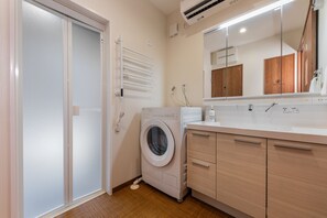 Ein modernes Badezimmer mit integrierter Waschmaschine, einem Spiegel und Holzschränken.