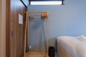 Ein kleiner, kompakter Raum mit einem Holzschrank, einem Bett mit weißer Bettwäsche, einem kleinen Fenster und einem Handtuchhalter.