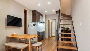 A modern kitchen with a dining area, wooden flooring, and a built-in TV. - Kikou (Kyoto)