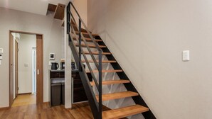 A modern staircase with wooden steps and metal railings leading to a landing. - Kikou (Kyoto)