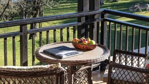 Un balcón con mobiliario de mimbre, una mesa con un frutero y un libro, y vistas a cebras en un parque.