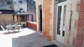 Un espace extérieur aménagé en terrasse, avec une table et des chaises, un petit marchepied et une porte.