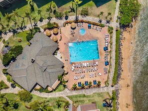 An aerial view of a resort with a swimming pool, sun loungers, and a beach area. - Large 1BR condo, partial ocean view, pool, beach access - Kaanapali Shores 414 (Lahaina)