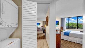 Une chambre d’hôtel avec un lit, un bureau, une chaise, une armoire et une vue sur la plage.