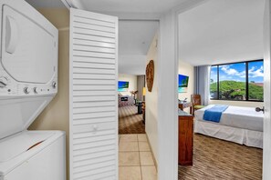 Ein Hotelzimmer mit Bett, Schreibtisch, Stuhl, Kleiderschrank und Blick auf einen Strand.