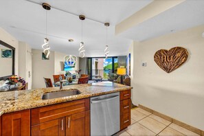 A modern kitchen with granite countertops, a built-in dishwasher, and pendant lighting. - Large 1BR condo, partial ocean view, pool, beach access - Kaanapali Shores 414 (Lahaina)