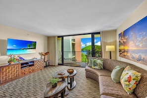 A hotel room with a balcony, a sofa, a TV, and a wooden cabinet.