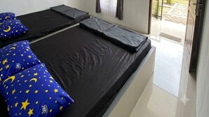 Ein Zimmer mit zwei Betten, einem an der Wand befestigten Fernseher und einer Tür zu einem Außenbereich.
