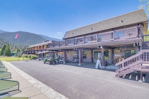 A building with a wooden facade, outdoor seating, and a mountain backdrop. - Mountain Air & Game Nights: Pine Mtn Club Cabin (Pine Mountain Club)
