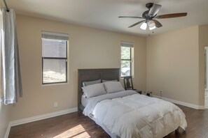 Ein Schlafzimmer mit einem Bett, einem Deckenventilator und zwei Fenstern.