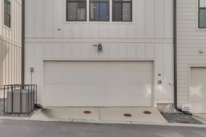 Un garaje residencial con una puerta blanca, una cámara de seguridad y un buzón.