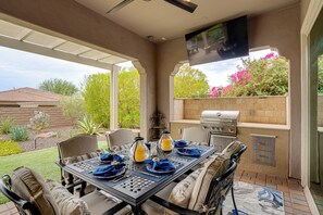 An outdoor patio with a table set for dining, a grill, and a view of the garden. - Elegant Home w/ Various Resort Perks in Peoria! (Peoria)