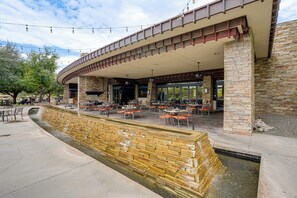 Un área de comedor al aire libre con paredes de piedra, mesas y sillas.