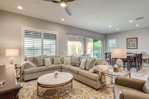 Ein Wohnzimmer mit einer Eckcouch, einem runden Couchtisch und einem Essbereich mit Tisch und Stühlen.