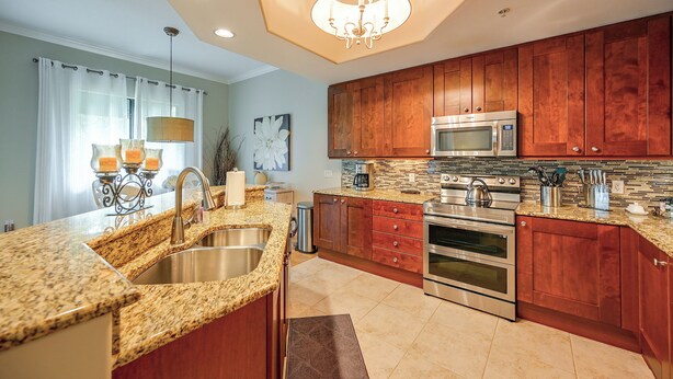 A modern kitchen with granite countertops, stainless steel appliances, wooden cabinets, and a chandelier. - Your Dream Vacation Awaits in Naples! Luxury Condo (Naples)
