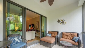 A sunlit patio with wicker furniture, a glass door leading to an indoor area, and a decorative wall piece. - Your Dream Vacation Awaits in Naples! Luxury Condo (Naples)
