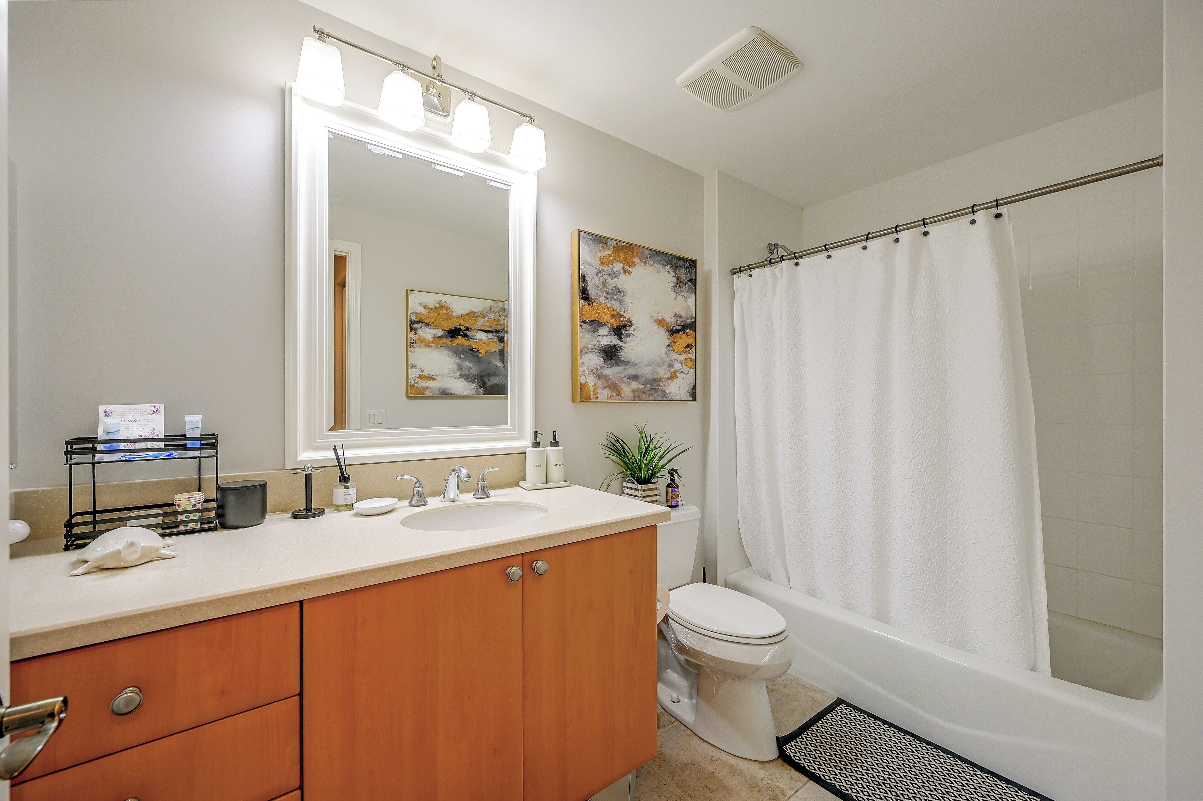 Un bagno con un mobile lavabo, un lavandino, uno specchio e una tenda per la doccia.