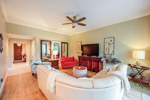 A spacious living room with a large sofa, a red armchair, and a television. - Your Dream Vacation Awaits in Naples! Luxury Condo (Naples)
