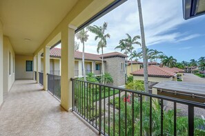 A balcony with a view of a residential area, including houses with red-tiled roofs and palm trees. - Your Dream Vacation Awaits in Naples! Luxury Condo (Naples)
