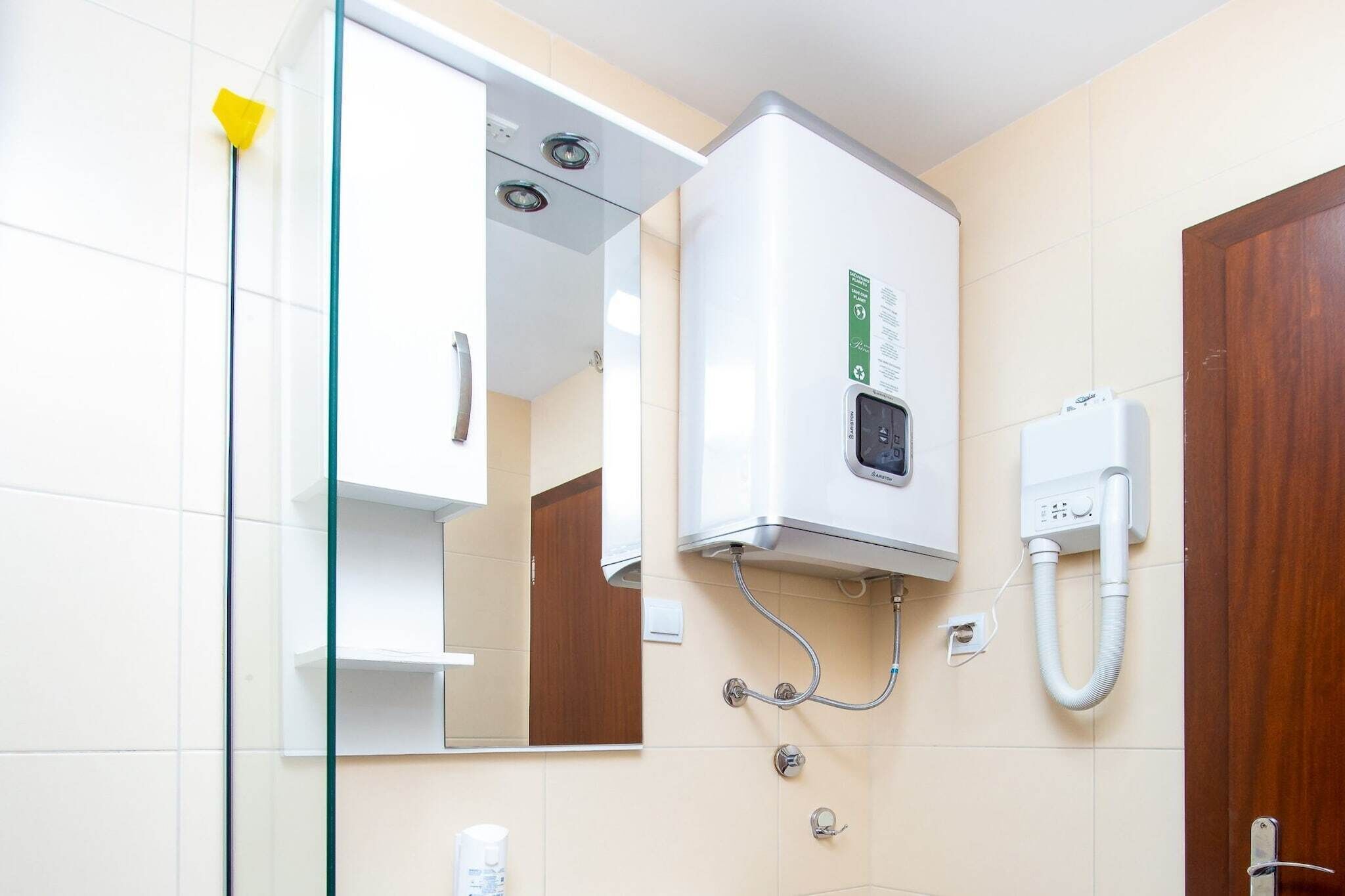Een badkamer met een witte verwarming, een spiegel en een houten deur.