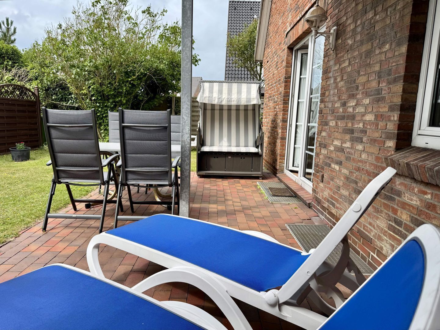 A patio with two lounge chairs, a table, and a barbecue grill.