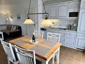 Ein Essbereich mit einem Holztisch, weißen Stühlen und einer Weinflasche.