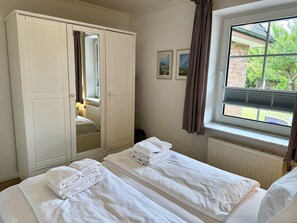 Ein Hotelzimmer mit zwei Betten, einem Kleiderschrank, einem Fenster mit Jalousien und einer Heizung.