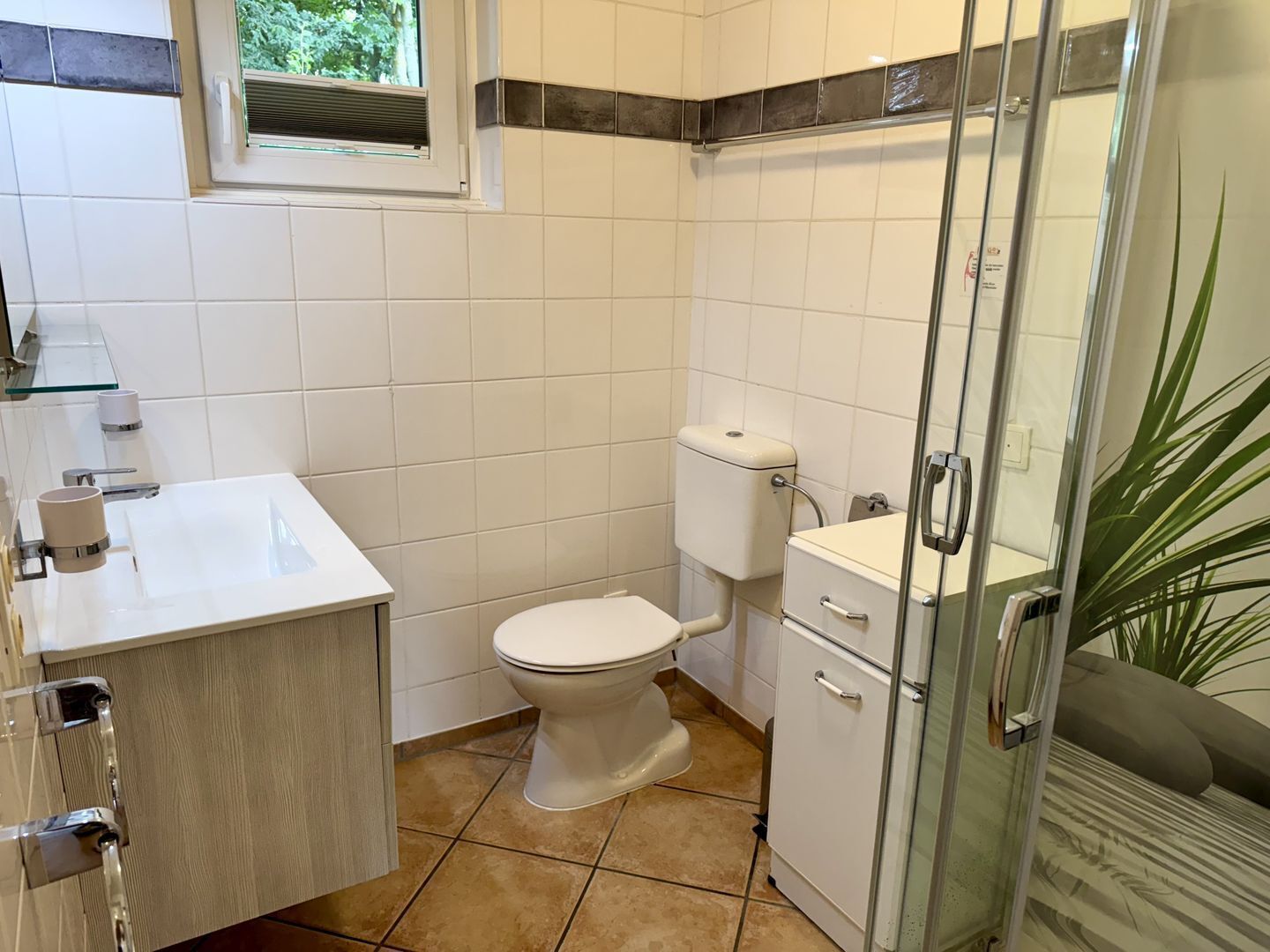 A bathroom with a toilet, sink, and shower area.