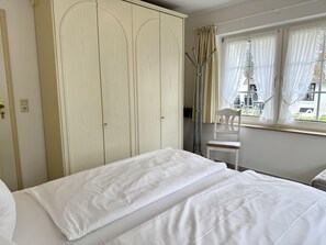 Un dormitorio con cama, armario y ventana con cortinas.