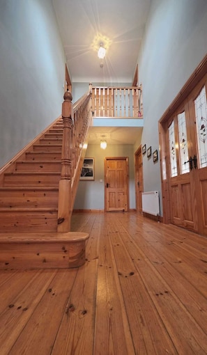 Eine Holztreppe führt zu einer oberen Ebene mit einem Balkon, einer Holztür und einer Fußbodenheizung.