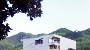 Un edificio moderno de varios pisos con techo plano, ventanas amplias y un balcón.