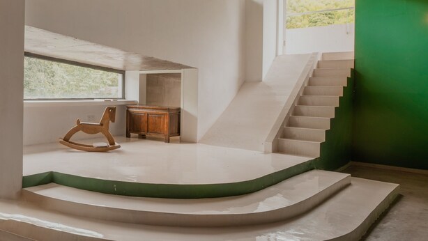 Un interior moderno con una escalera, una mecedora y un escritorio.