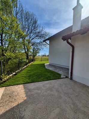 A residential property with a well-maintained lawn, a white building with a red roof, and a stone pathway leading to the entrance.