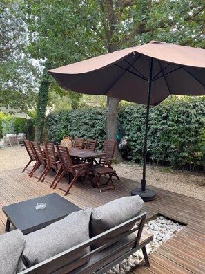 An outdoor patio with a table and chairs, a bench, and a large umbrella.