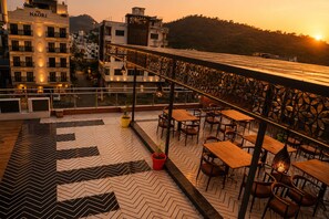 Una terraza en la azotea con mobiliario exterior y vistas a la ciudad al atardecer.