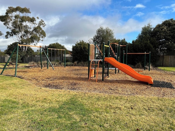 A playground with swings, a slide, and climbing structures.