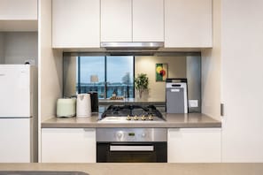 Eine moderne Küche mit Gasherd, Backofen und Blick auf die Stadt durch große Fenster.