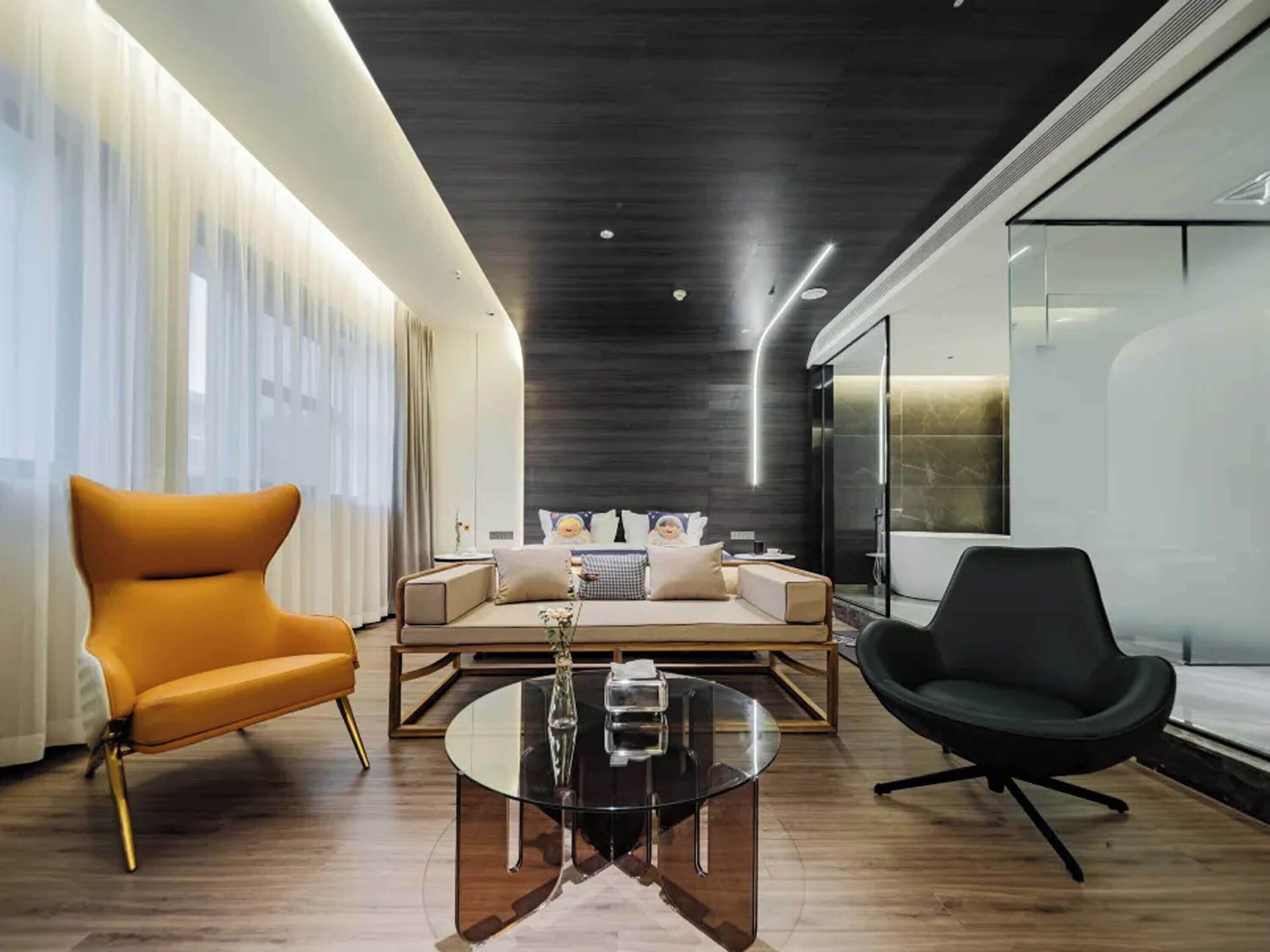 Un salon moderne avec un canapé, des fauteuils et une table basse en verre.