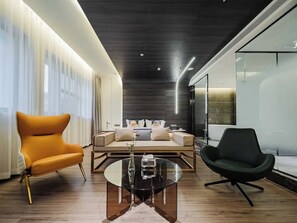 A modern living room with a sofa, armchairs, and a glass coffee table. - Xian Jing - Scenery Hotel (Xi'an)