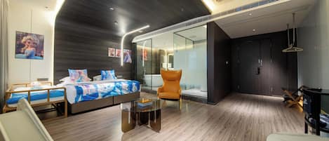 Une chambre d’hôtel moderne dotée d’un grand lit, d’un coin salon avec une table en verre et d’une salle de bain séparée avec une baignoire.