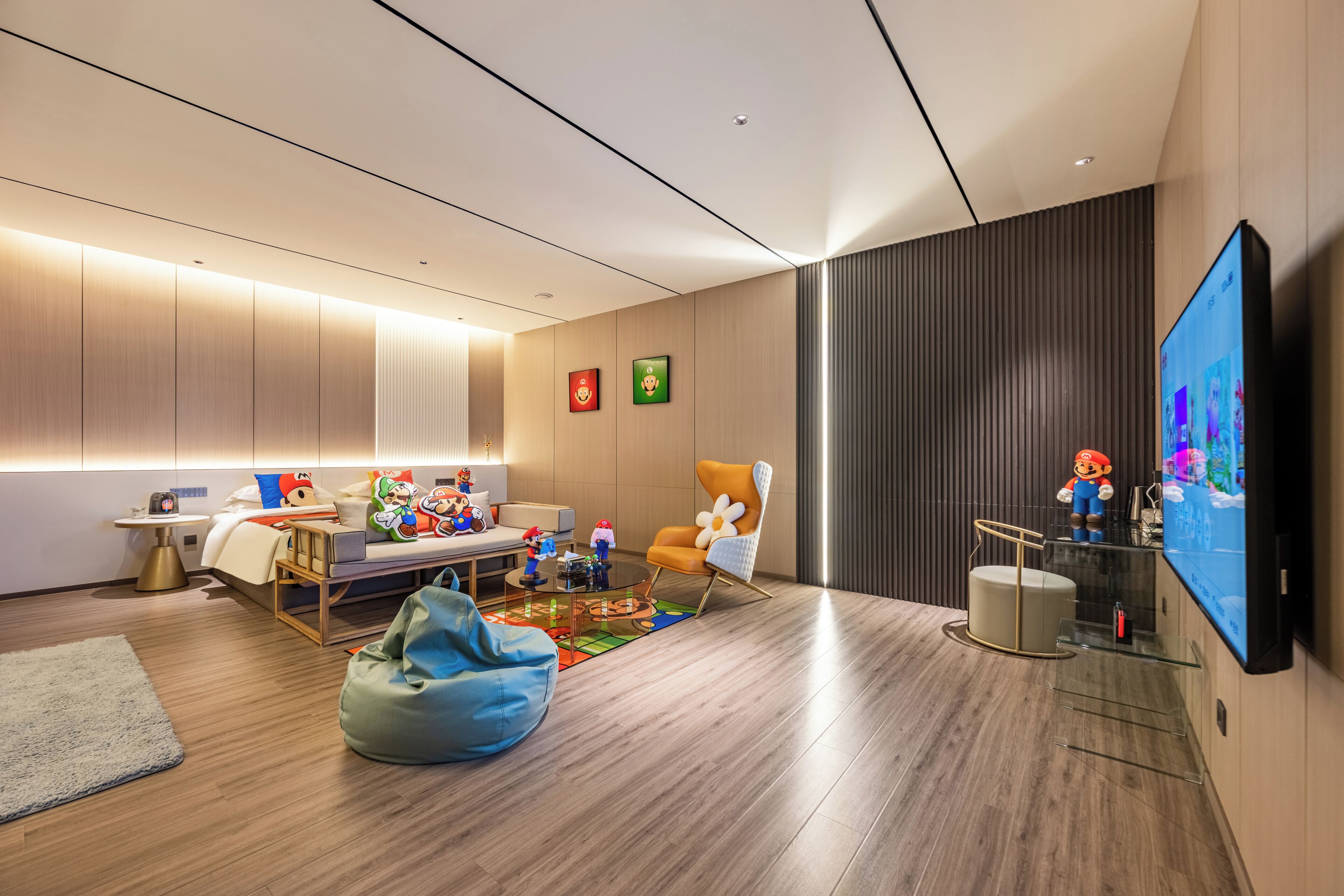 A modern living room with a flat-screen TV, a sofa, a coffee table, and a bean bag.