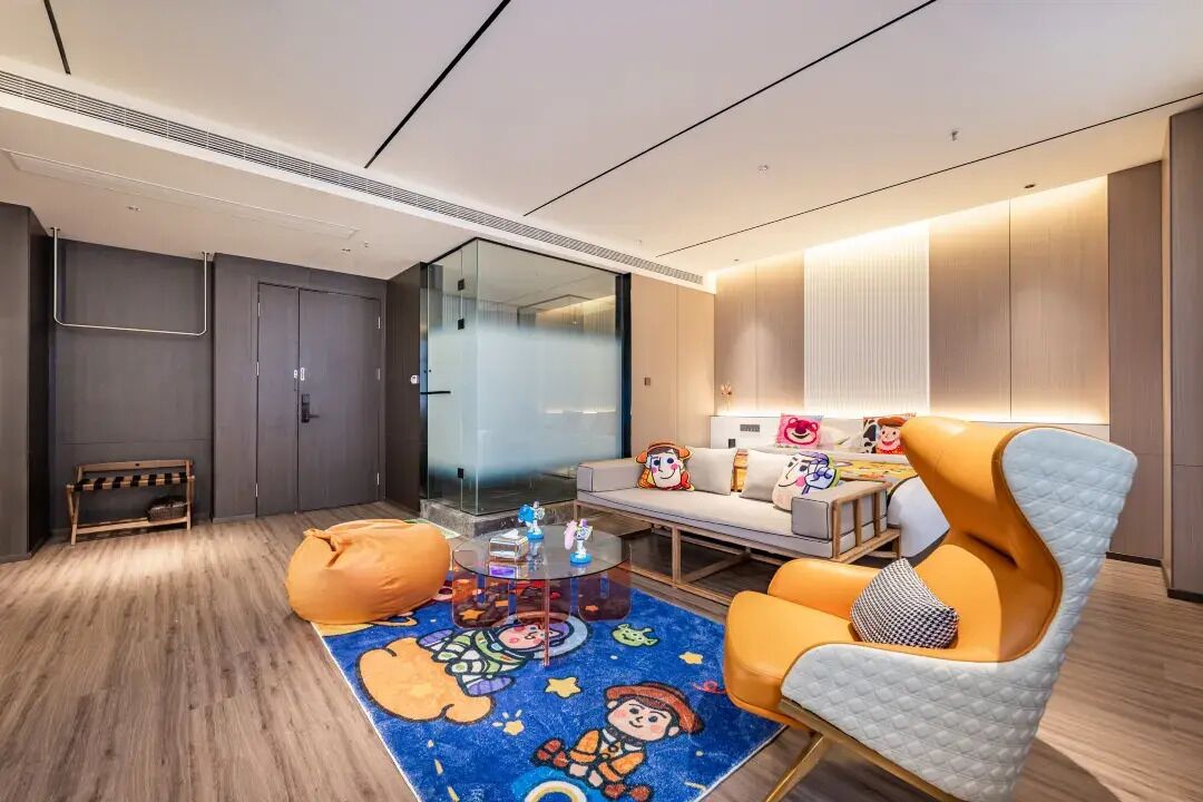 A modern hotel room with a sofa, armchair, and a round coffee table.