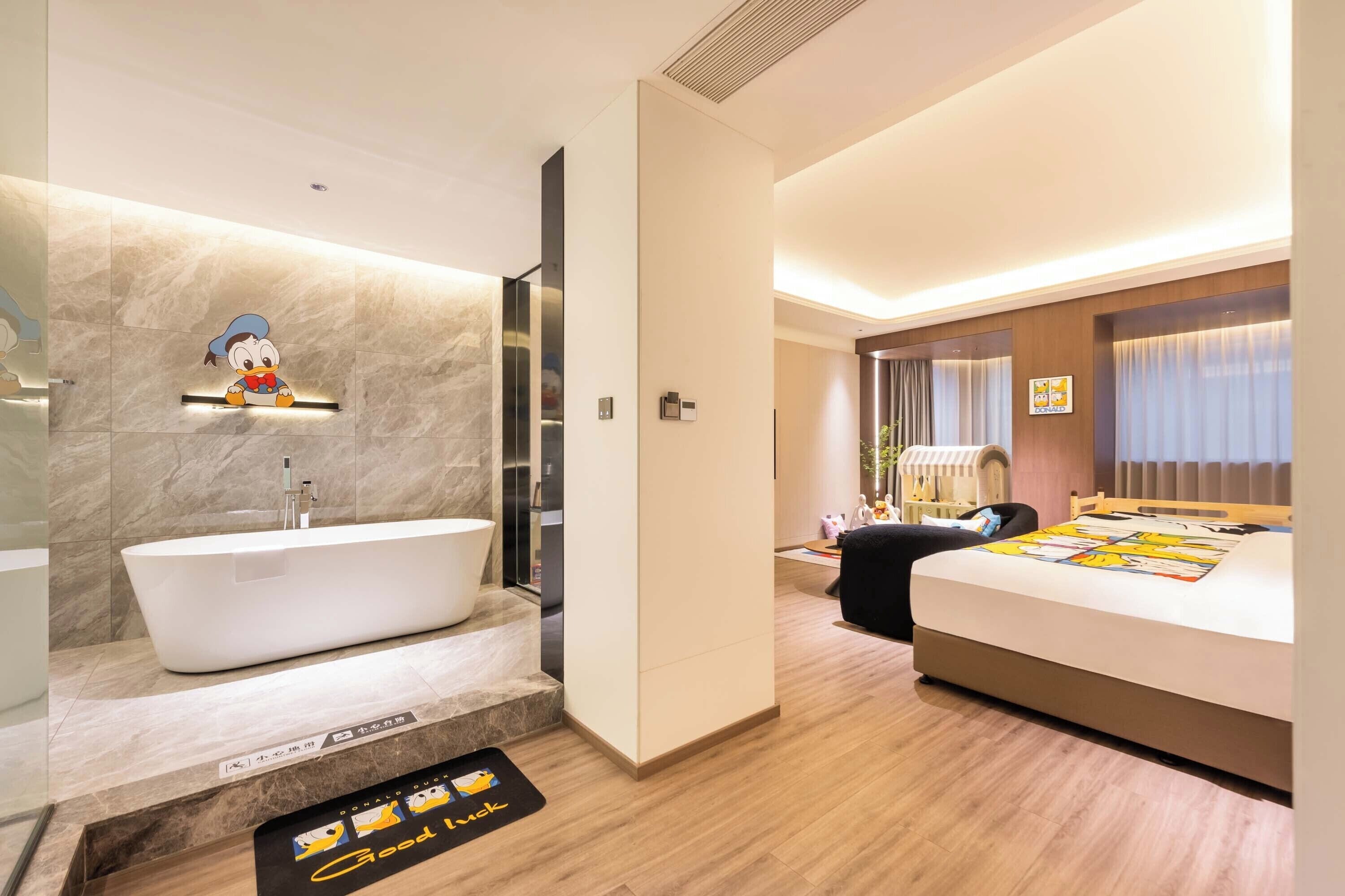 A hotel room with a bathtub, a bed, a desk, and a window with curtains.