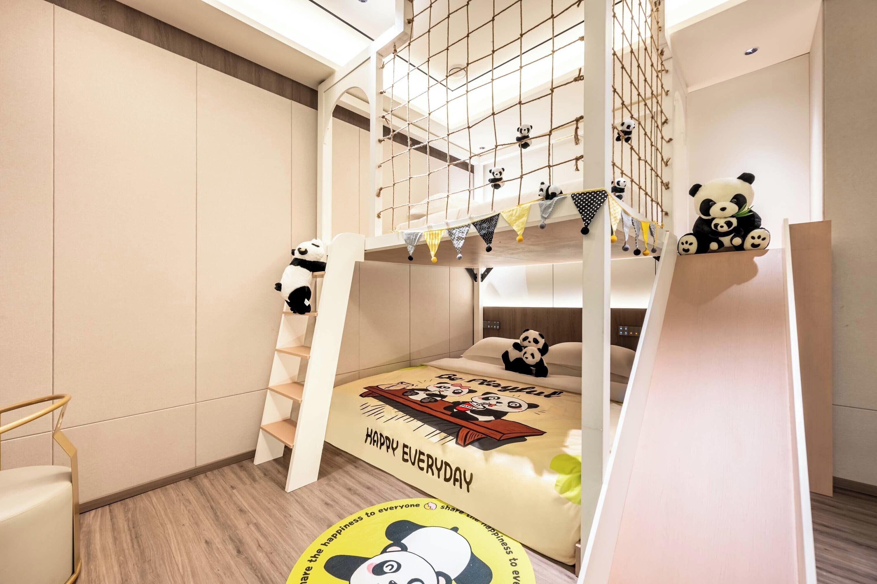 Habitación con literas decorada con temática de panda, que incluye un peluche de panda en la cama y un panda en la pared.